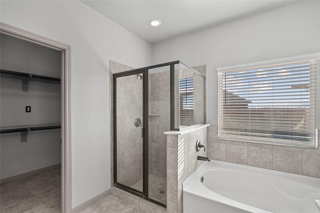 full bathroom with a shower stall, baseboards, a walk in closet, and a bath