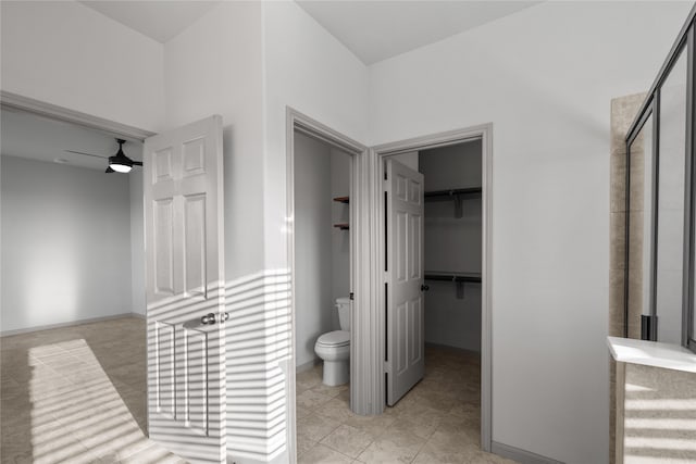 interior space featuring toilet, tile patterned floors, ceiling fan, and an enclosed shower