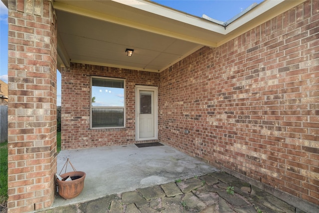 property entrance featuring a patio area and brick siding