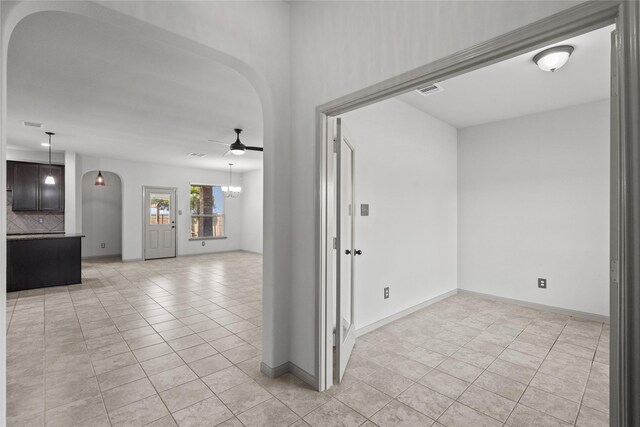 unfurnished room featuring ceiling fan with notable chandelier and light tile patterned floors