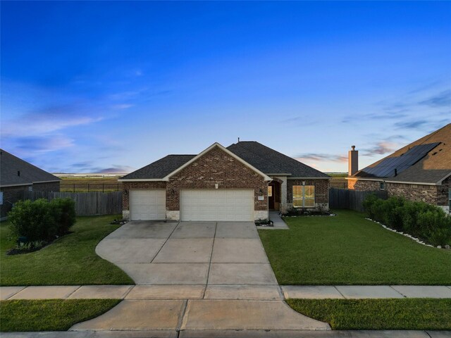 ranch-style house with solar panels, a garage, and a lawn