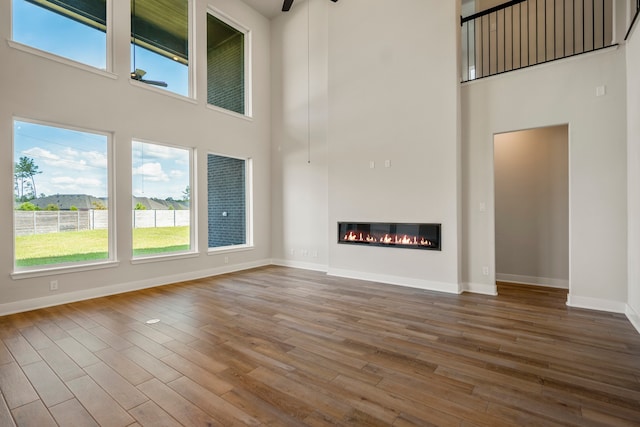 unfurnished living room with wood-type flooring and a high ceiling