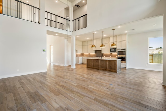 interior space with sink, light hardwood / wood-style flooring, and a towering ceiling