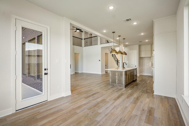 unfurnished living room with light hardwood / wood-style floors, sink, and ceiling fan