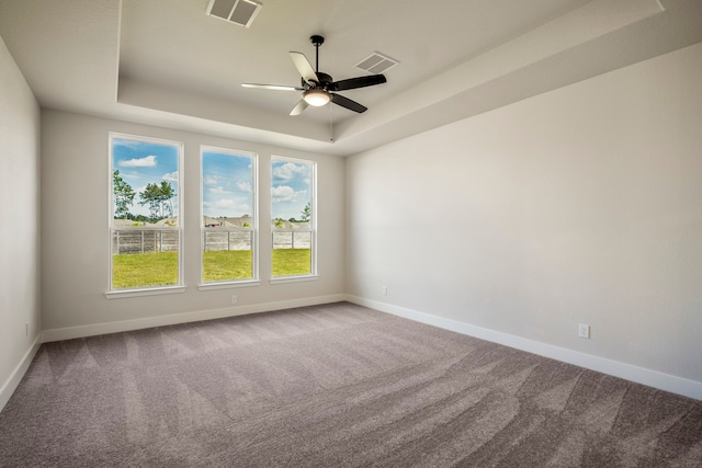 empty room with carpet, ceiling fan, and a raised ceiling