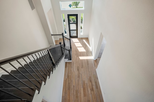 stairs featuring a towering ceiling and light wood-type flooring