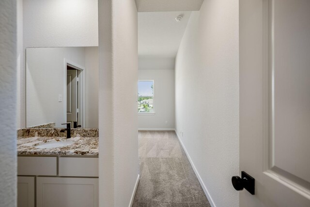 corridor with sink and light colored carpet