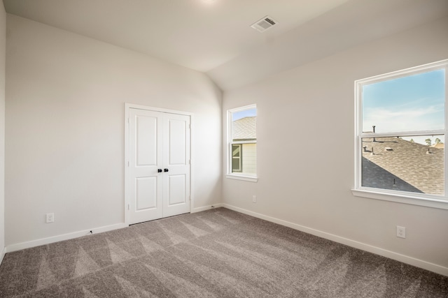 unfurnished room featuring carpet floors, vaulted ceiling, and a healthy amount of sunlight