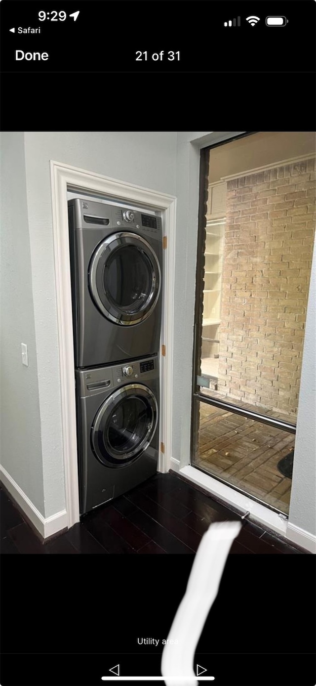 laundry area featuring stacked washer / drying machine and dark hardwood / wood-style floors