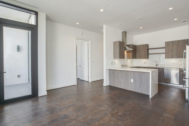 kitchen featuring sink, decorative backsplash, appliances with stainless steel finishes, and wall chimney exhaust hood