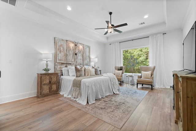 bedroom with ceiling fan, light wood-type flooring, crown molding, and a tray ceiling