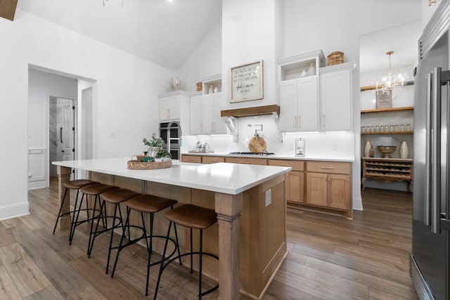 kitchen with stainless steel appliances, dark hardwood / wood-style floors, a kitchen breakfast bar, white cabinets, and a spacious island