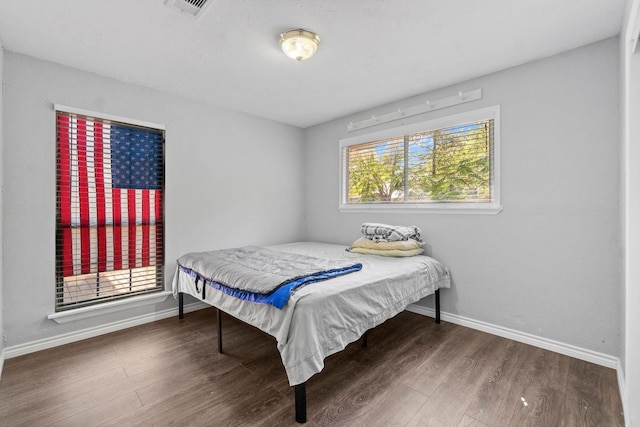 bedroom with visible vents, baseboards, and wood finished floors