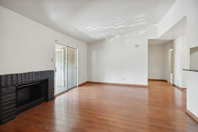 unfurnished living room with a brick fireplace and hardwood / wood-style floors