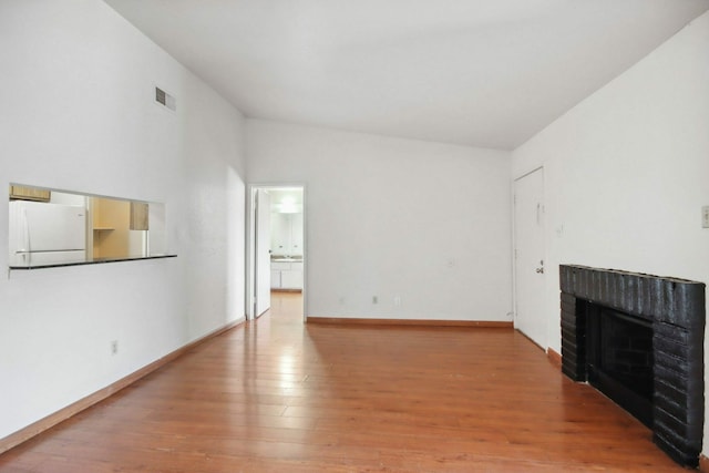 unfurnished living room with a fireplace, lofted ceiling, and hardwood / wood-style floors