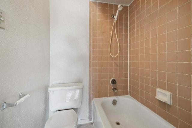 bathroom with tiled shower / bath combo and toilet