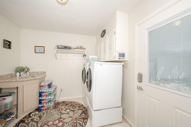 laundry room featuring light tile patterned flooring, washing machine and dryer, crown molding, and cabinets