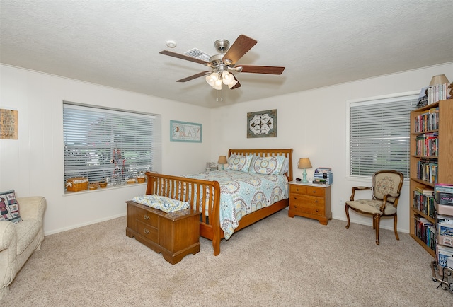 bedroom with light carpet, ceiling fan, and a textured ceiling