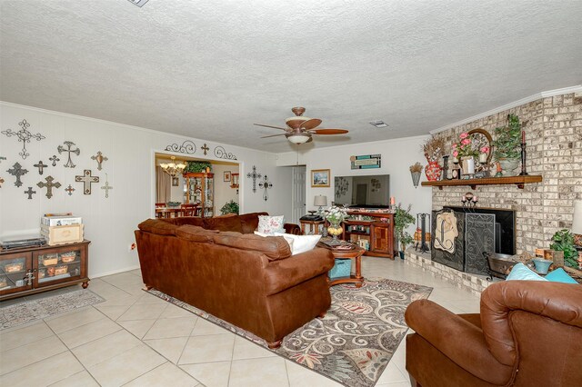 tiled living room with crown molding, ceiling fan with notable chandelier, a brick fireplace, and a textured ceiling