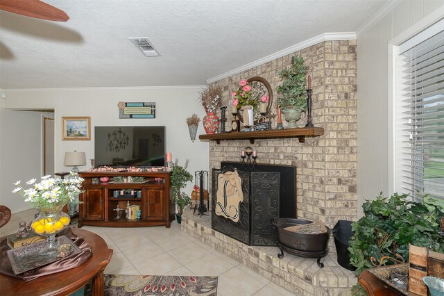 living room featuring light tile patterned floors, a textured ceiling, a brick fireplace, ceiling fan, and ornamental molding