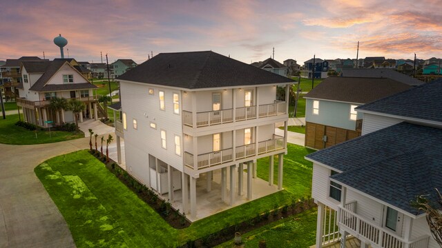 back house at dusk with a yard and a balcony