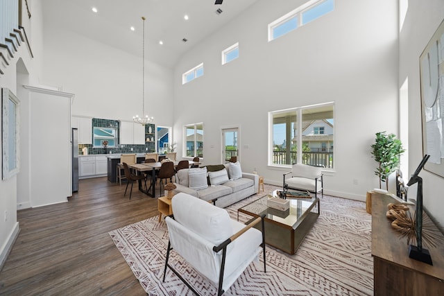 living room featuring hardwood / wood-style flooring, a towering ceiling, and a chandelier