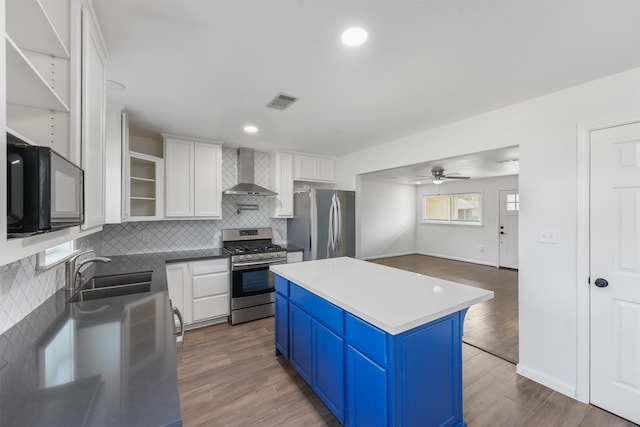 kitchen with hardwood / wood-style flooring, stainless steel appliances, wall chimney exhaust hood, and sink