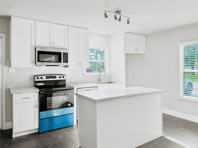 kitchen with white cabinetry, stainless steel appliances, a center island, light stone countertops, and sink