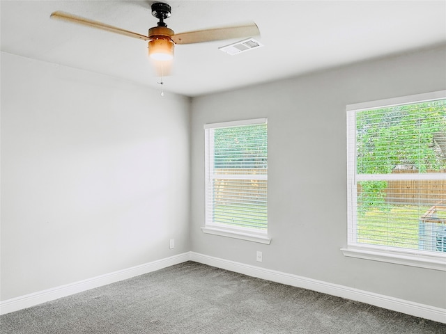 empty room featuring a healthy amount of sunlight, ceiling fan, and carpet flooring