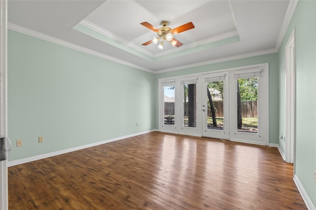 empty room featuring a tray ceiling, ceiling fan, crown molding, and wood-type flooring