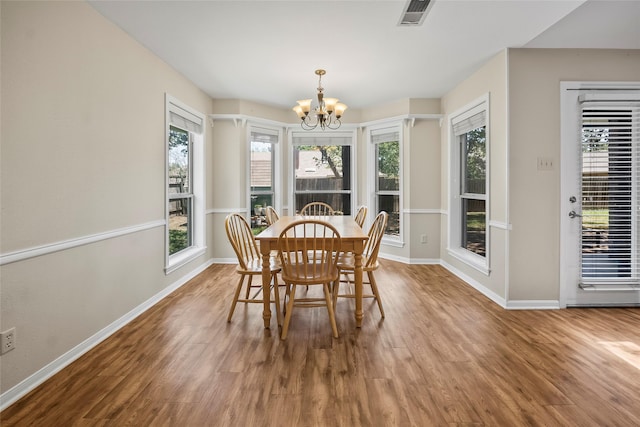 dining area with an inviting chandelier, a wealth of natural light, and hardwood / wood-style floors