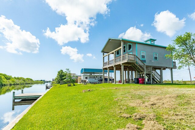 rear view of house with a lawn and a deck with water view