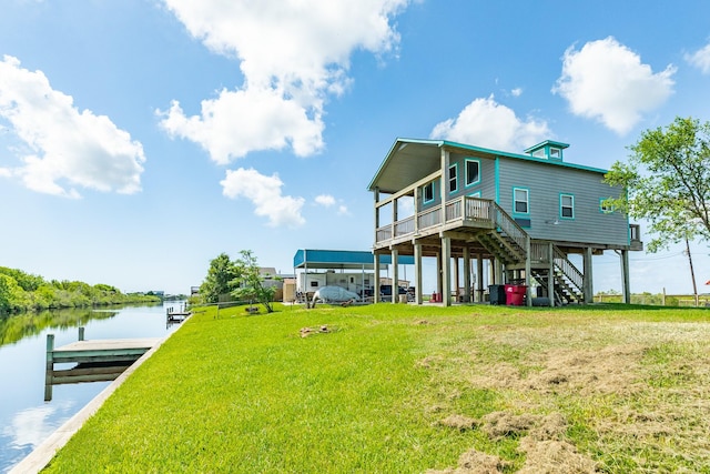 rear view of house featuring a deck with water view and a lawn
