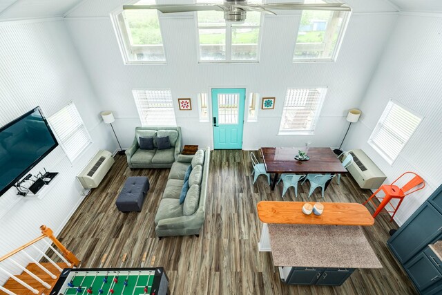 living room with ceiling fan, a high ceiling, a wall unit AC, and dark wood-type flooring