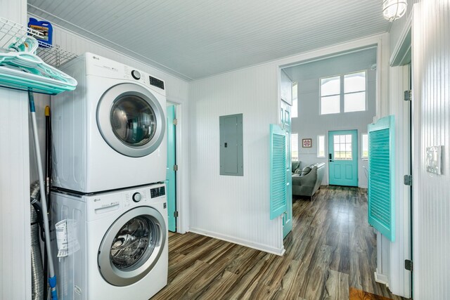 washroom featuring crown molding, electric panel, stacked washer and clothes dryer, and dark hardwood / wood-style flooring