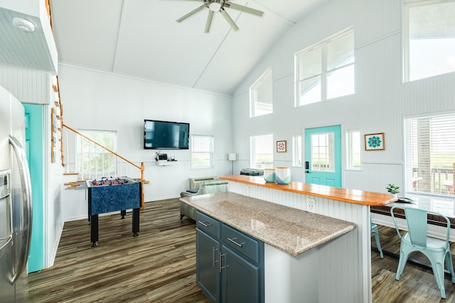 kitchen with ceiling fan, stainless steel refrigerator with ice dispenser, light stone countertops, gray cabinetry, and dark hardwood / wood-style flooring