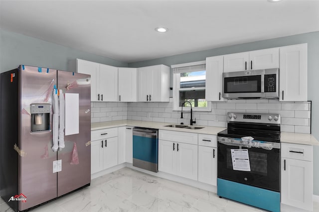 kitchen with light tile patterned floors, white cabinets, appliances with stainless steel finishes, decorative backsplash, and sink