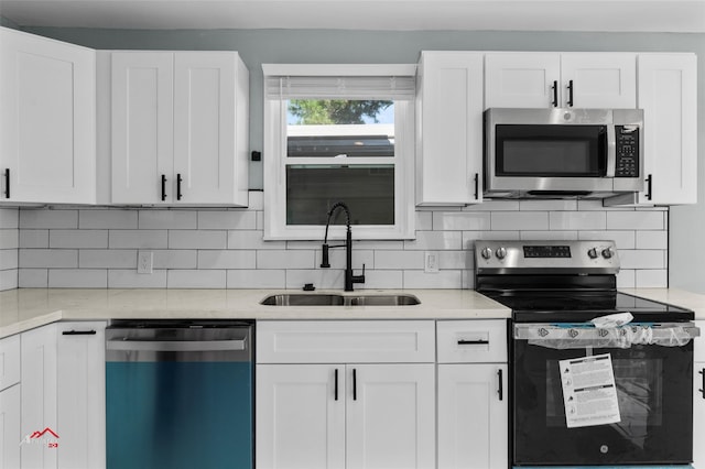 kitchen featuring sink, light stone countertops, stainless steel appliances, and white cabinetry