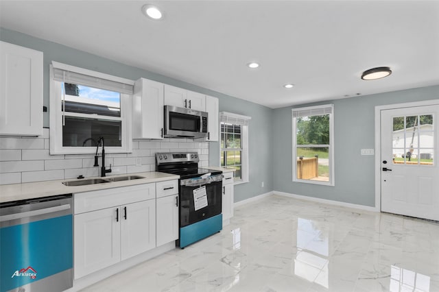 kitchen featuring white cabinets, backsplash, appliances with stainless steel finishes, and sink