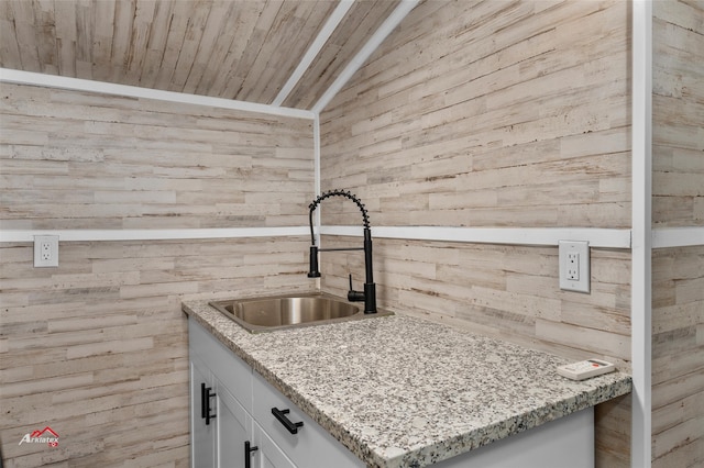 kitchen with wood walls, wooden ceiling, white cabinets, and vaulted ceiling