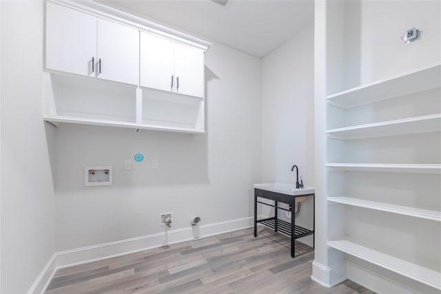 laundry room featuring cabinets, electric dryer hookup, light hardwood / wood-style flooring, hookup for a washing machine, and gas dryer hookup