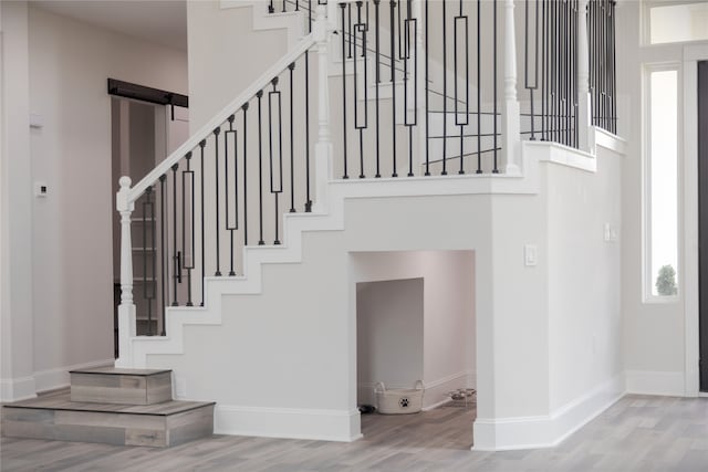 stairs with light wood-type flooring and a barn door