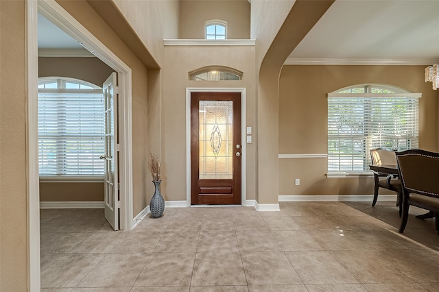 foyer with crown molding and light tile patterned floors