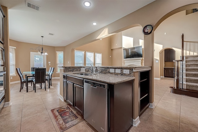 kitchen featuring hanging light fixtures, an island with sink, stainless steel appliances, dark brown cabinets, and sink