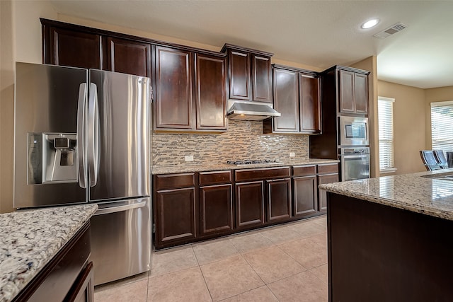 kitchen featuring appliances with stainless steel finishes, dark brown cabinetry, light tile patterned floors, and light stone counters