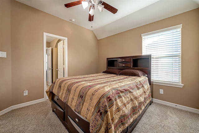 carpeted bedroom with ceiling fan, ensuite bath, vaulted ceiling, and multiple windows