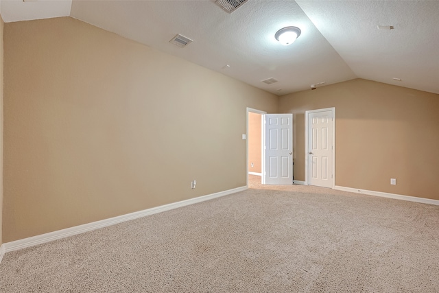 unfurnished room with carpet flooring, a textured ceiling, and vaulted ceiling