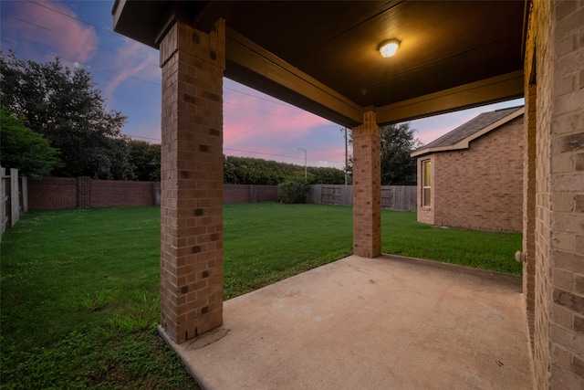 patio terrace at dusk featuring a yard