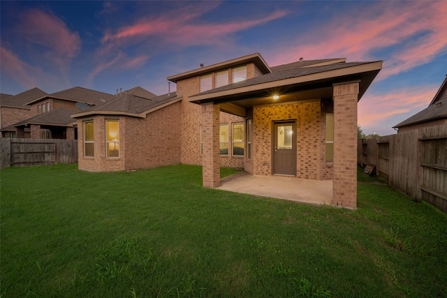 back house at dusk featuring a patio and a yard