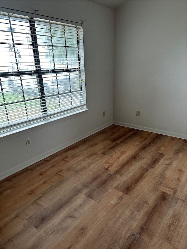 empty room with plenty of natural light and hardwood / wood-style flooring